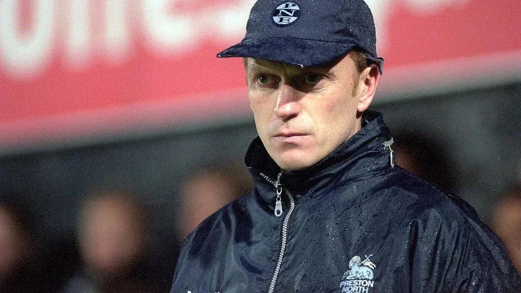 Coach in raincoat and cap on the sidelines