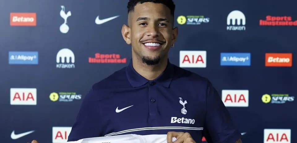 Player holding Tottenham Hotspur jersey at press conference