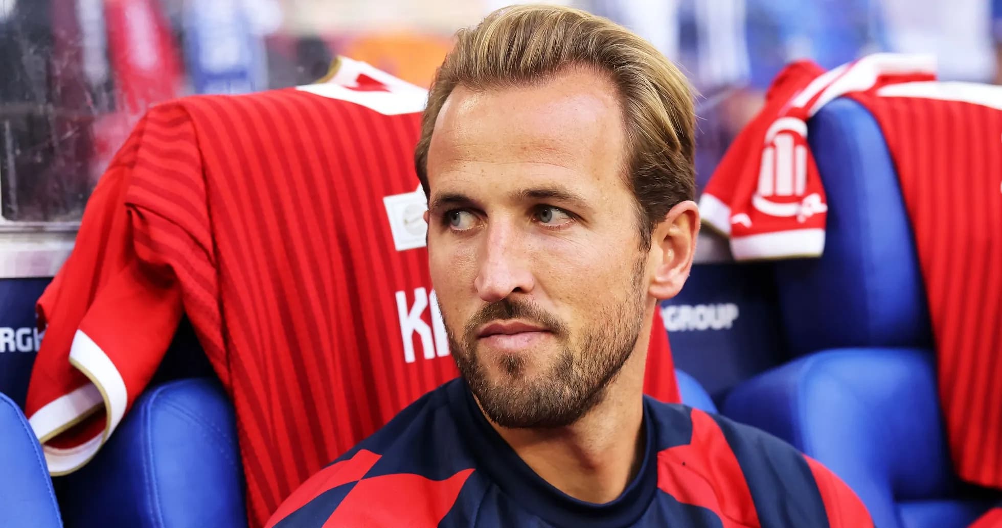Player sitting on bench with red jerseys behind