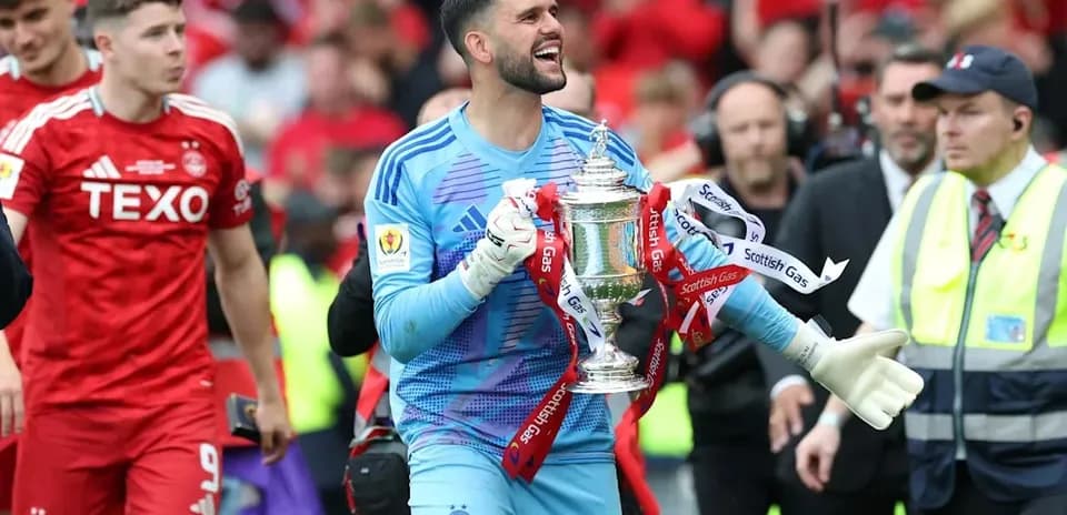 Goalkeeper celebrating with trophy after match victory