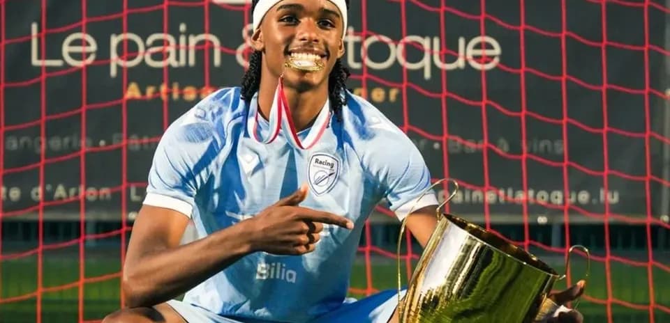 Player celebrating with trophy in front of goal