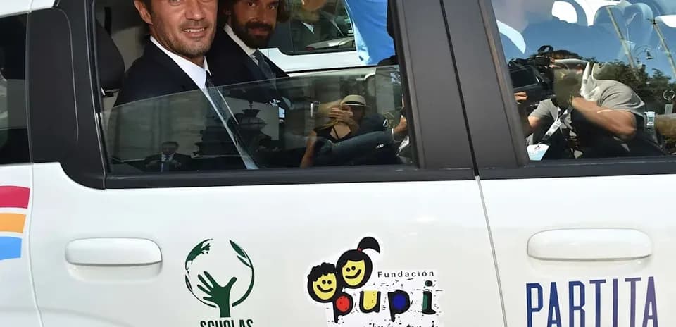 Two men in a car with charity logos visible