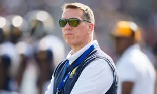 Man wearing sunglasses observing a football game