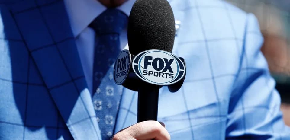 Person holding FOX Sports microphone in blue suit