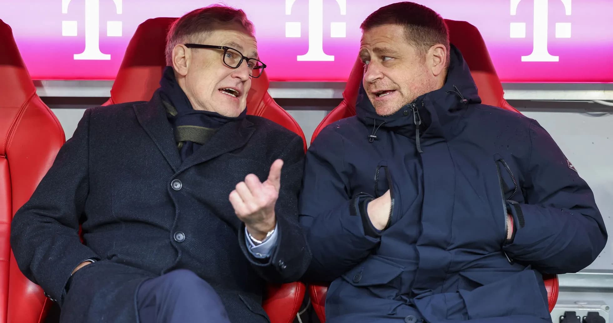Two men conversing on team bench during match