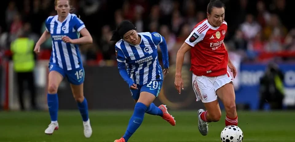 Arsenal player dribbling past Brighton defenders during match