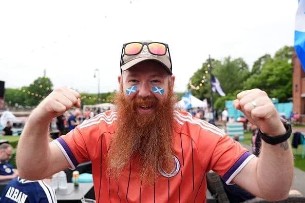 Fan celebrating with Scottish flags on face