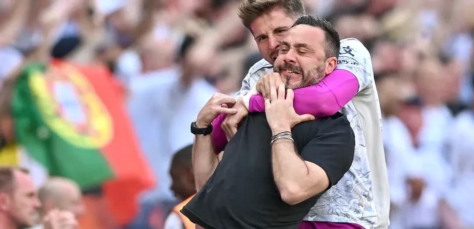 Two coaches celebrating with a hug during match