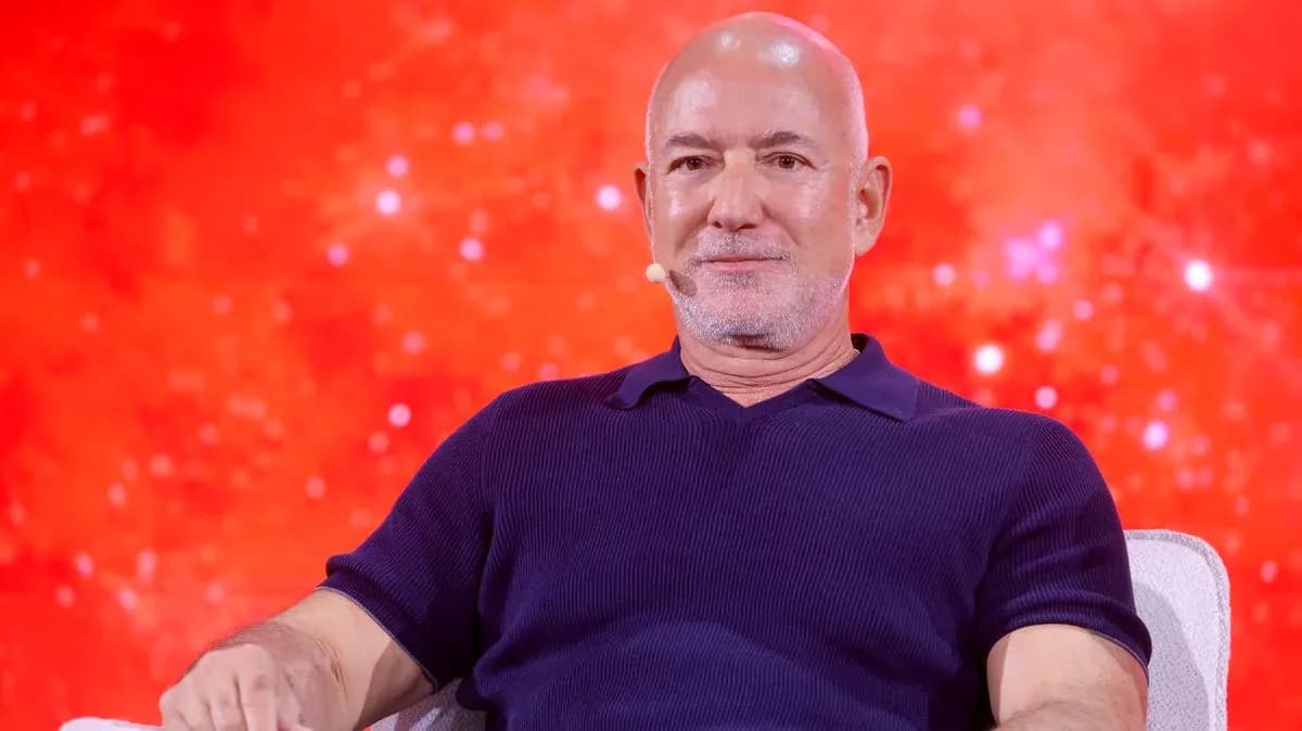 Man seated on stage with a red background
