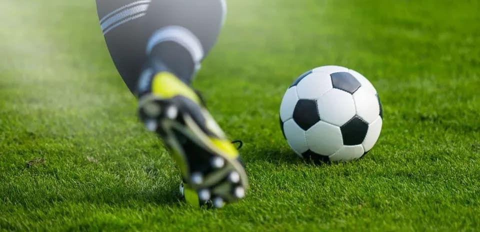 Player kicking a soccer ball on grass field