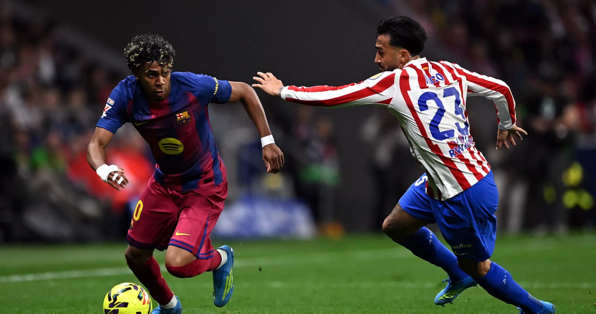 Barcelona player dribbling past Atletico Madrid defender