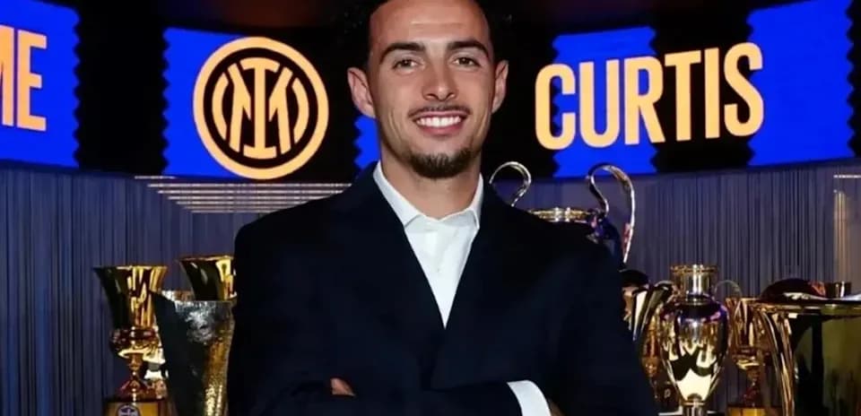 Person smiling in front of trophies and banners