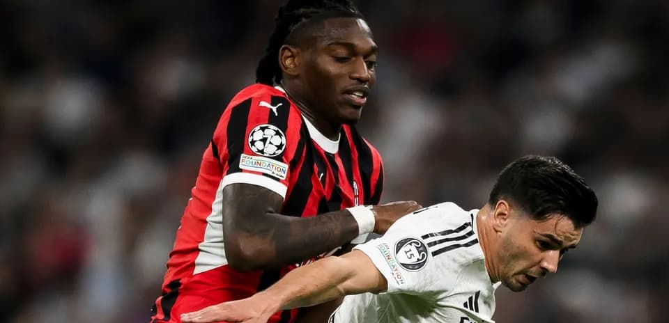 Player in red and black tackling opponent in white