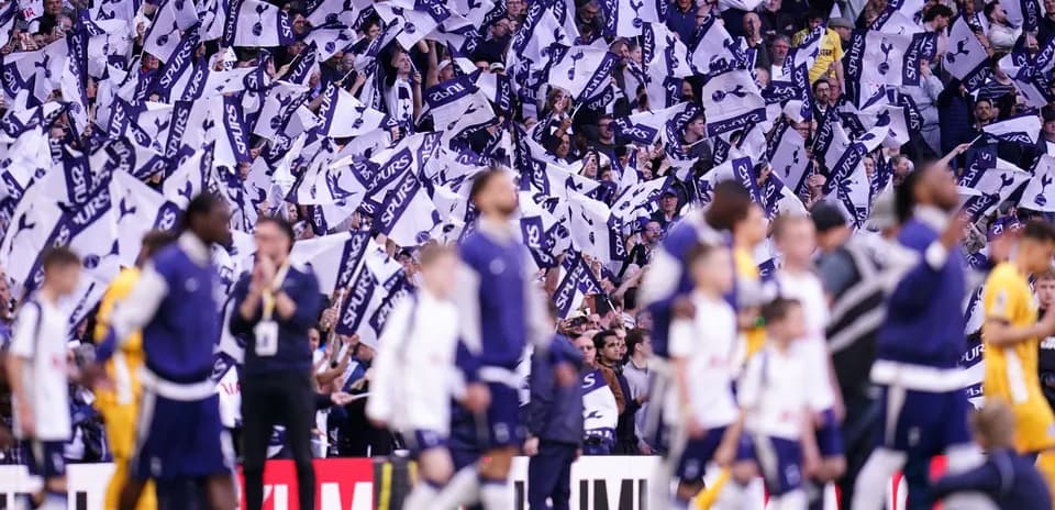 Fans waving flags in Tottenham Hotspur stadium