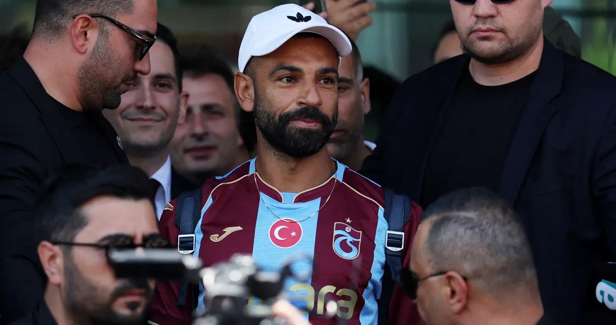 Player in Trabzonspor jersey surrounded by security personnel