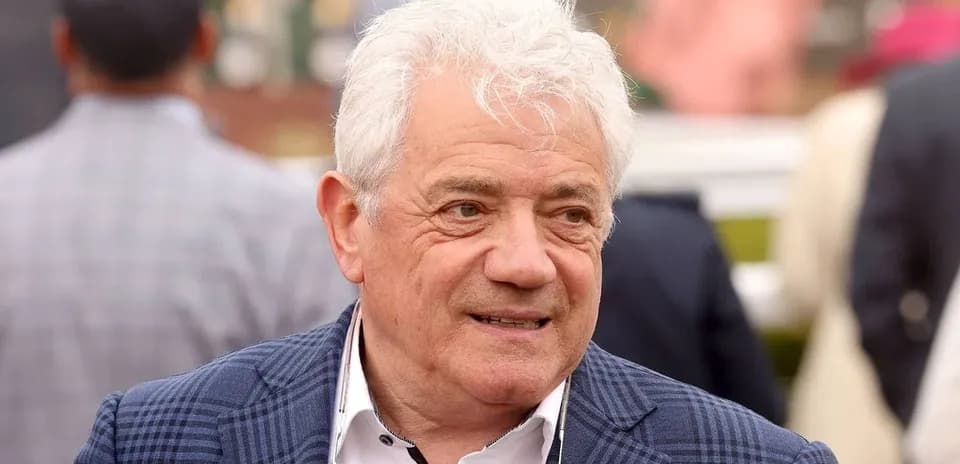 Man with white hair wearing a blue checked jacket