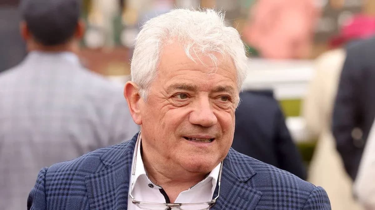 Man with white hair wearing a blue checked jacket