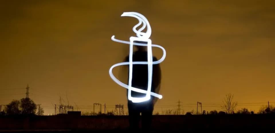 Person creating light drawing against dark background