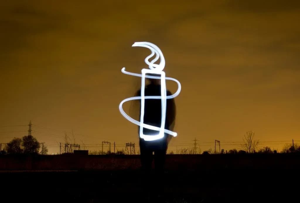 Person creating light drawing against dark background
