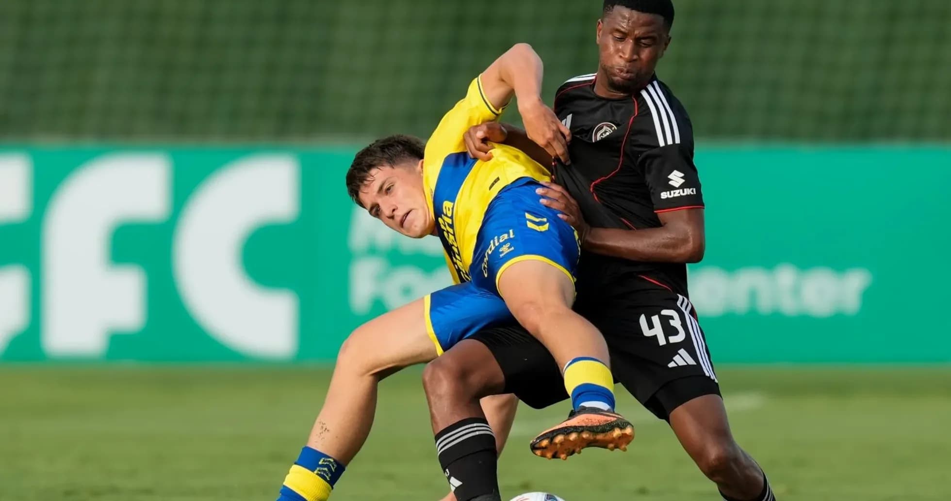 Player in yellow being tackled by opponent in black