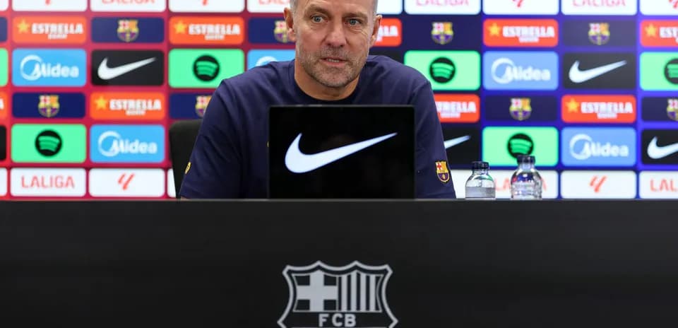 Manager speaking at press conference with team logos