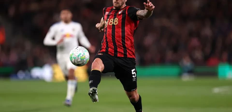 Player kicking ball during match with opposing player in background