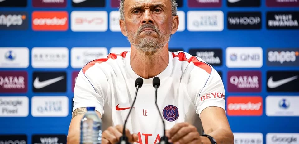 Manager at press conference with team branding behind
