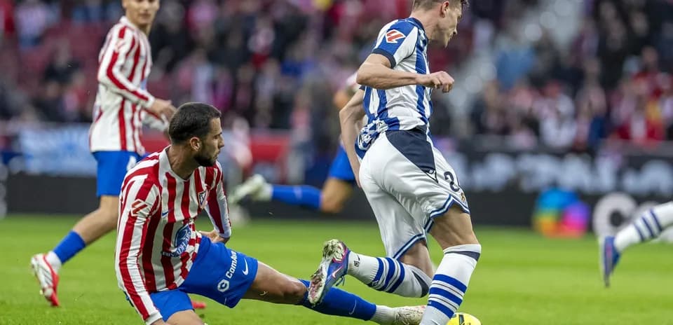 Real Sociedad player tackles Atletico Madrid opponent