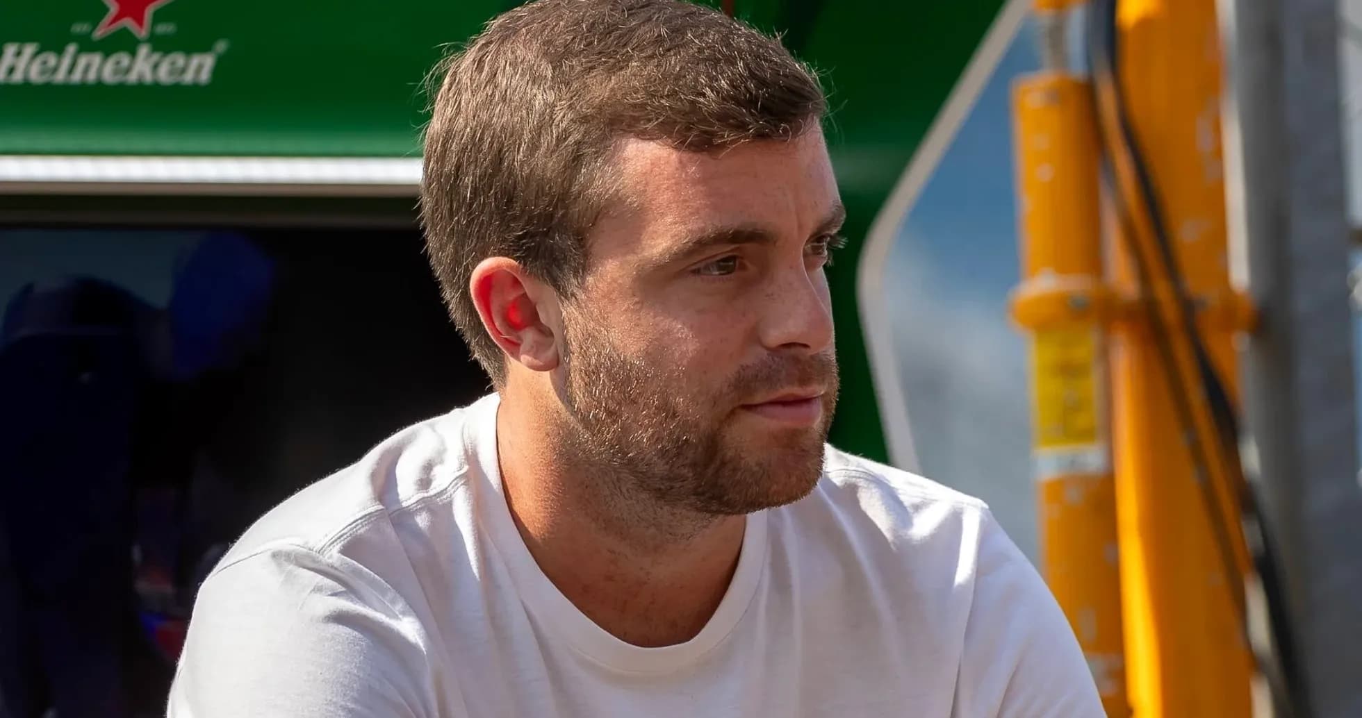 Man in white shirt sitting near a green backdrop