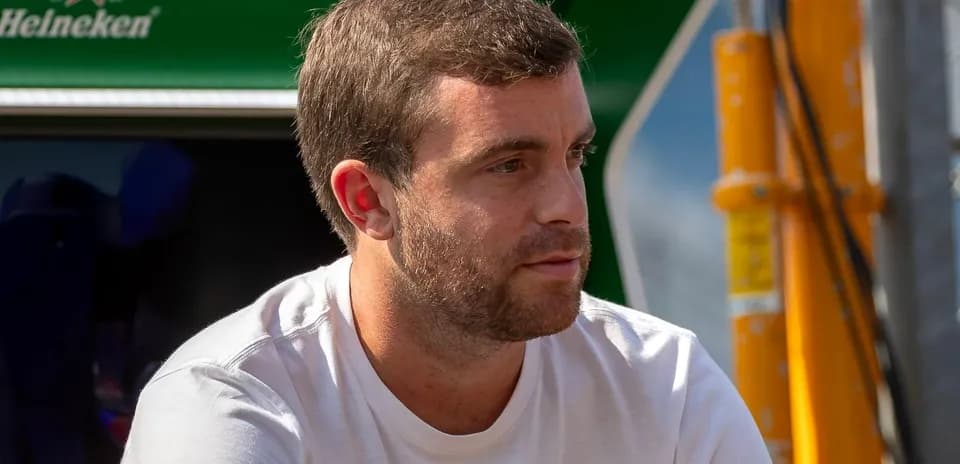 Man in white shirt sitting near a green backdrop