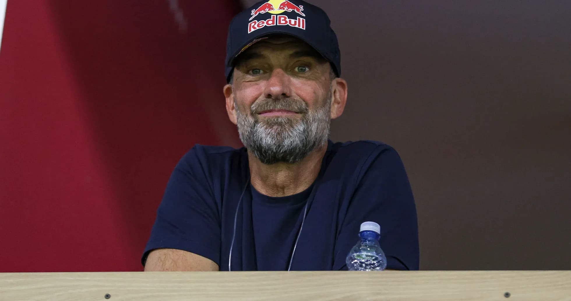 Man with beard wearing Red Bull cap watching event