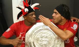 Two players celebrating with a trophy in locker room