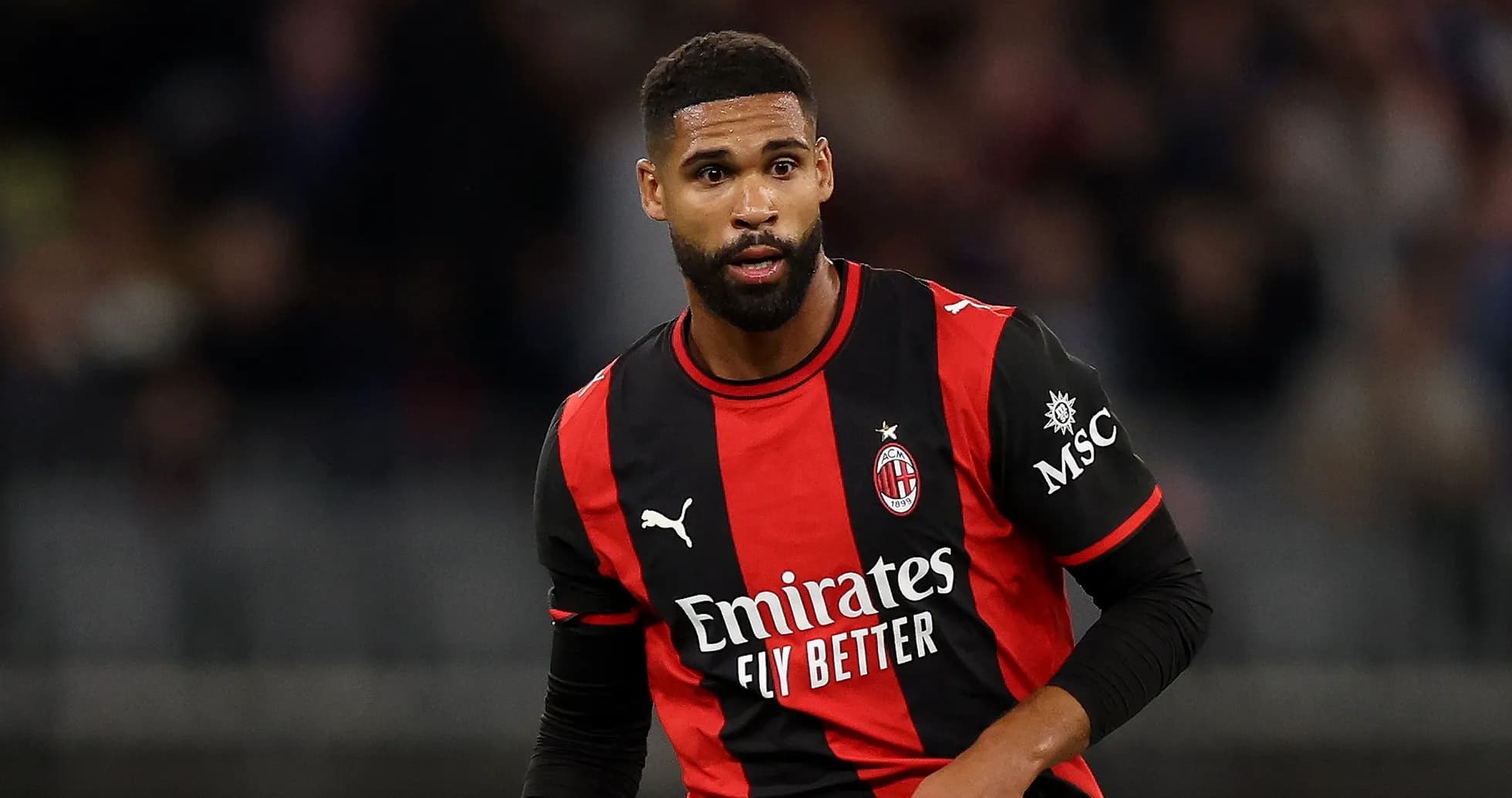 AC Milan player in black and red jersey on field