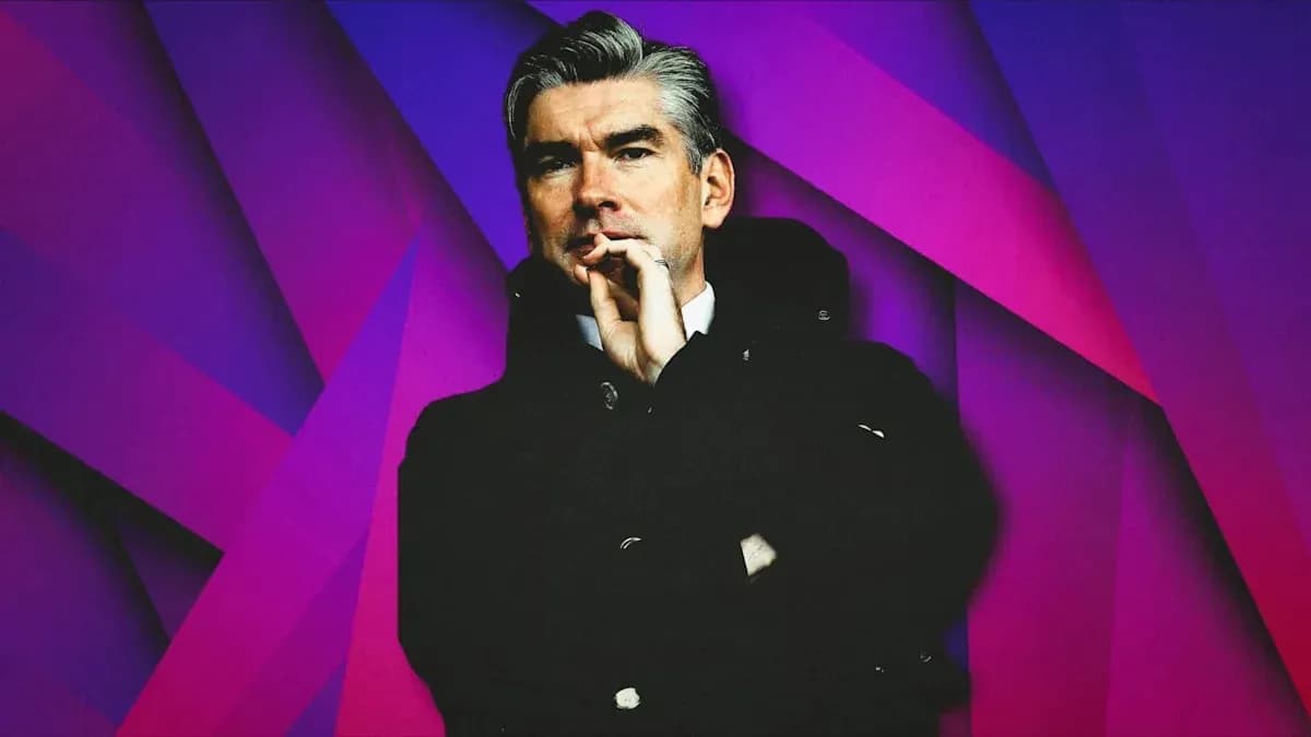 Man in coat with hand on chin against colorful background
