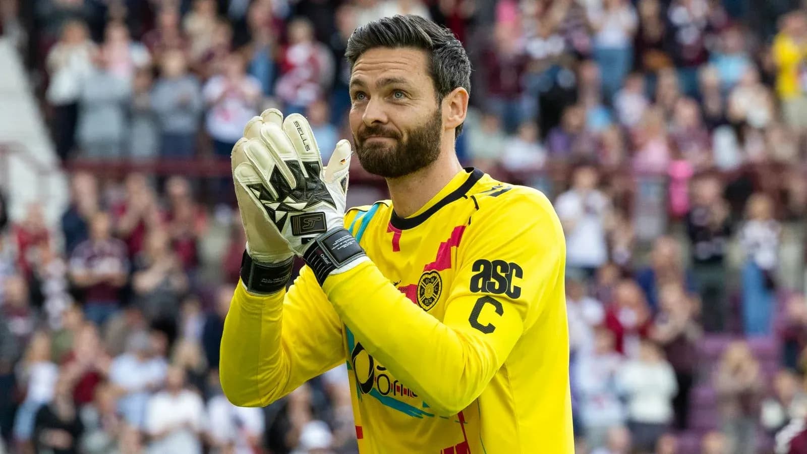 Goalkeeper applauding fans in yellow jersey