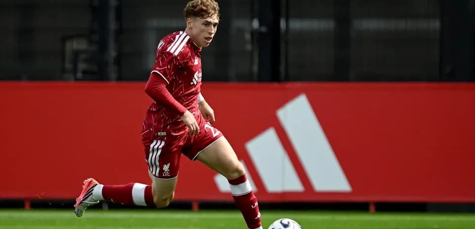 Player in red kit sprinting towards soccer ball