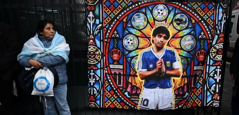 Woman with Argentine flag near mural of Maradona