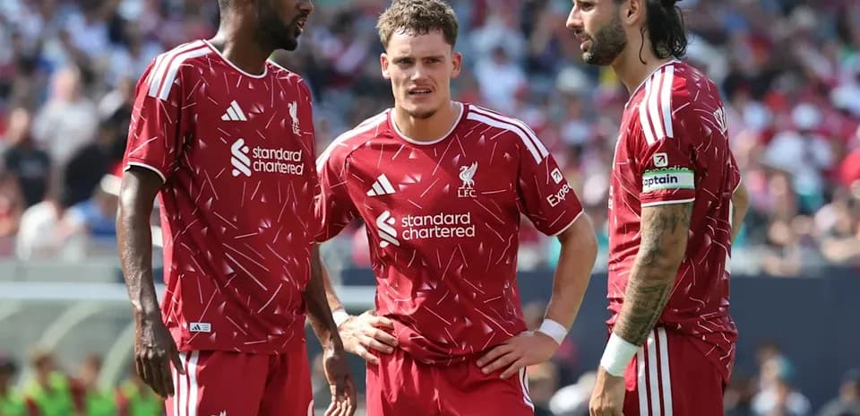 Three Liverpool players discussing on the field
