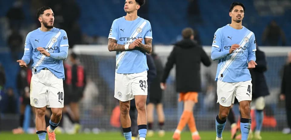 Three Manchester City players walking off the pitch