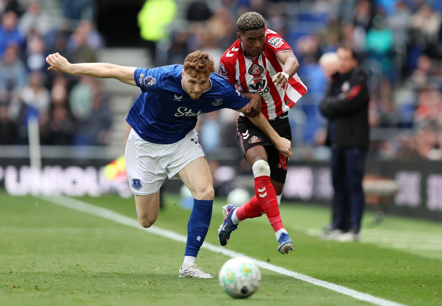 Everton player challenges Sunderland opponent for the ball