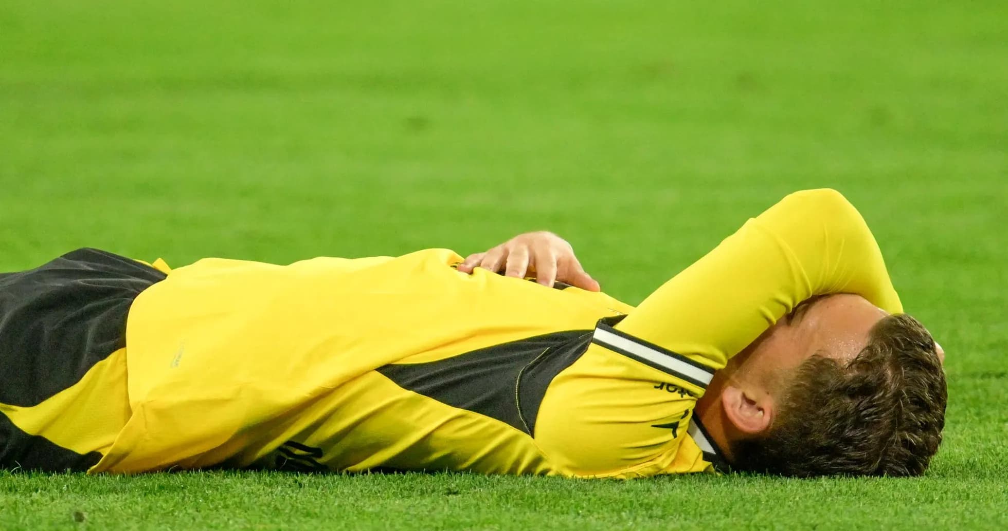 Player lying on field with hands over face