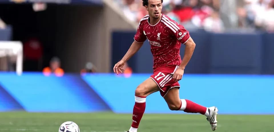 Player in red Liverpool kit dribbling ball on field