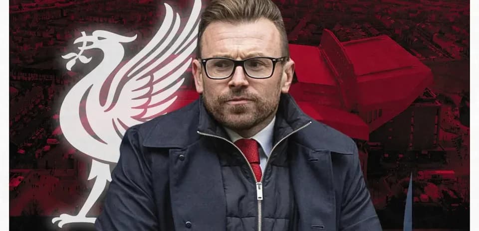 Man in glasses in front of Liverpool logo