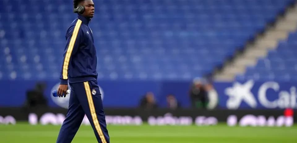 Player walking on pitch wearing headphones and tracksuit