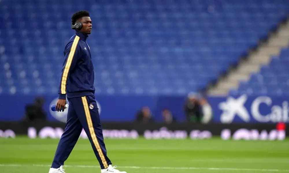 Player walking on pitch wearing headphones and tracksuit