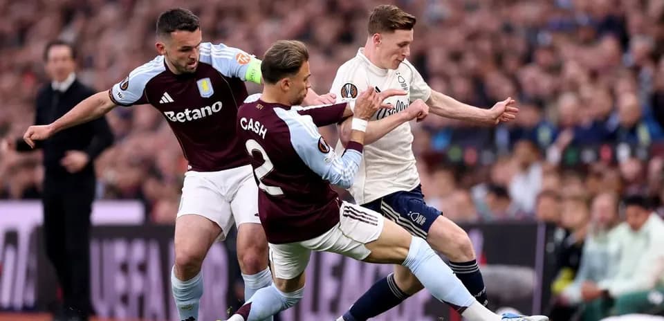 Two Aston Villa players tackling an opponent during match