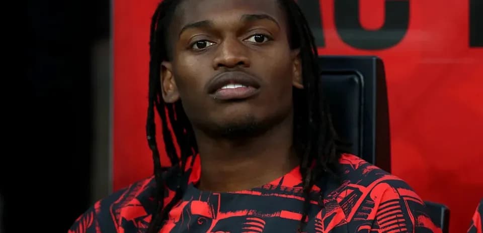Player seated on bench wearing AC Milan jersey