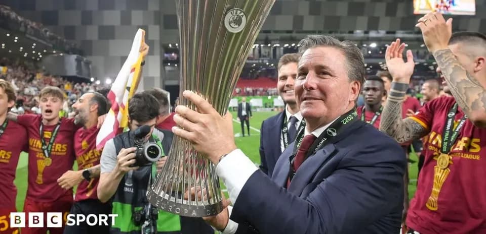 Manager celebrating with UEFA trophy and team members