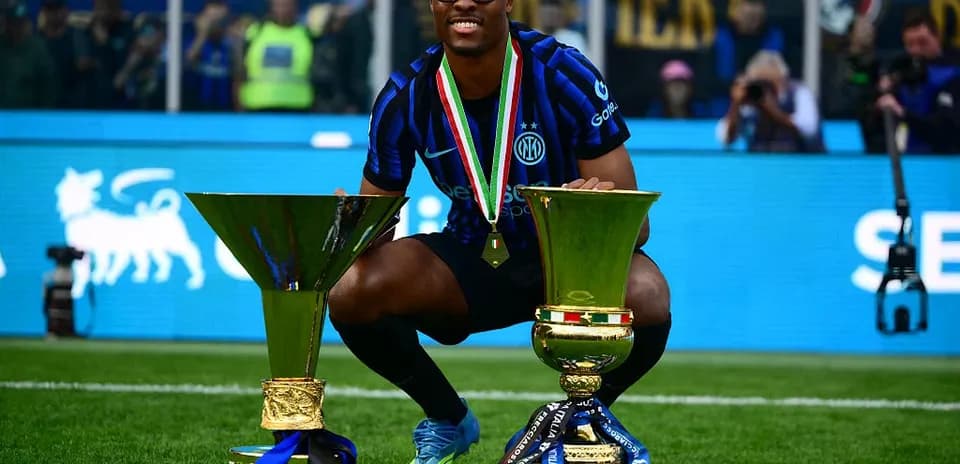 Player celebrating with two trophies on pitch