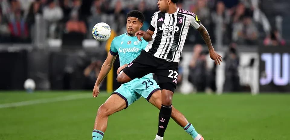 Juventus player challenging Bologna defender for the ball